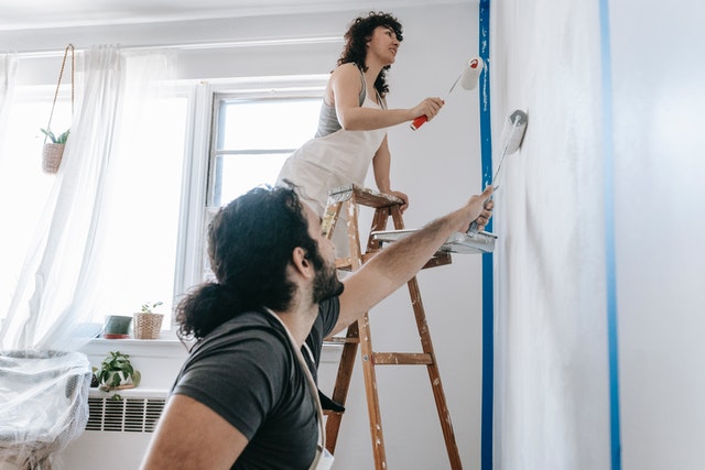 A couple painting a wall together.