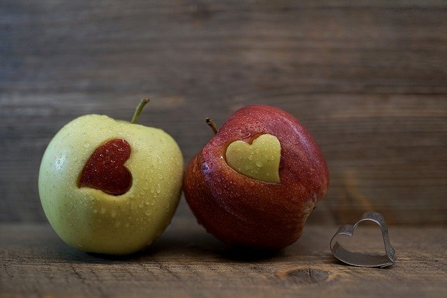 A green apple with a red heart and a red apple with a green heart