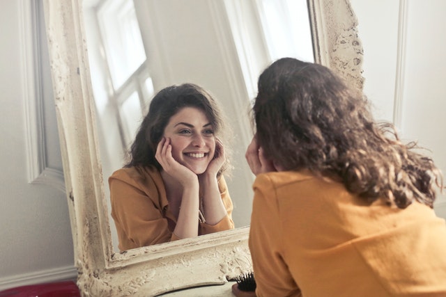 A girl smiling at herself in a mirror
