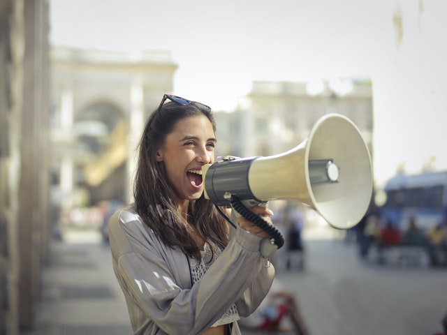 A girl happily yelling into a megaphone